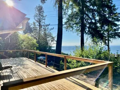 a wooden deck with a view of the ocean at Cedar House Ocean View & Access in Roberts Creek