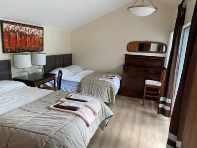 a bedroom with two beds and a desk and a dresser at Cedar House Ocean View & Access in Roberts Creek