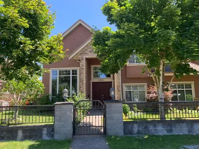 a brown house with a black gate and trees at Sakura Stay two bedrooms with a private bathroom in Richmond