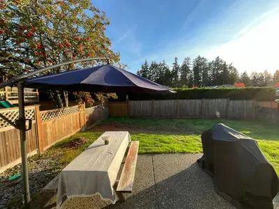 a picnic table under an umbrella in a backyard at LF Guesthouse in Nanaimo