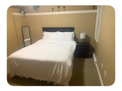 a bed with white sheets and pillows in a bedroom at Lower suite in family friendly townhome in Victoria