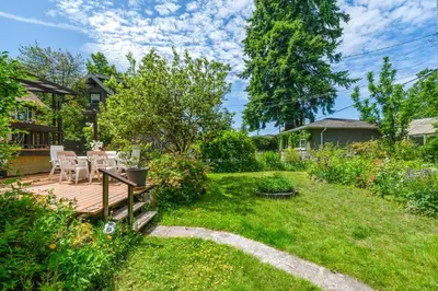 a backyard with a wooden deck with a table and chairs at Picturesque room surrounded by flowers with share spaces in Vancouver