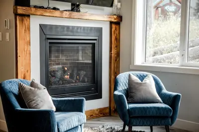 a living room with two chairs and a fireplace at 4-bedroom with Game Room & Hot Tub in Fernie