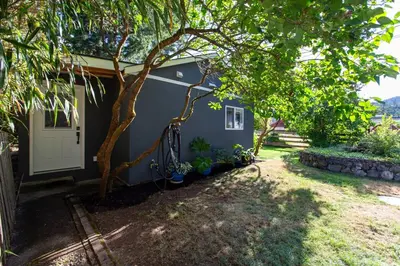 a blue house with a tree in front of it at Cozy 1-Bedroom Retreat in the Heart of Langford in Victoria