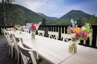 a long table with flowers in vases on a deck at Off-Grid Mountain Lodge & 4 Cabins - Sauna, Hot Tub & Fishing in Rock Lake Provincial Park