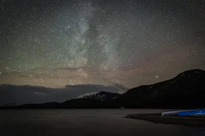 a starry night with the milky way over the water at Off-Grid Mountain Lodge & 4 Cabins - Sauna, Hot Tub & Fishing in Rock Lake Provincial Park