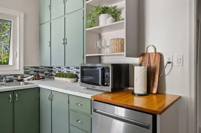 a kitchen with blue cabinets and a microwave on a counter at Kinepik Cottage Sunroom with Beach Access in Sylvan Lake