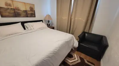 a bedroom with a white bed and a black chair at 4-Bedroom Home by Downtown and Airport in Calgary