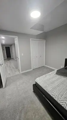 an empty bedroom with a bed and a hallway at Spruce Meadows Place in Calgary