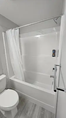 a white bathroom with a toilet and a bath tub at Spruce Meadows Place in Calgary