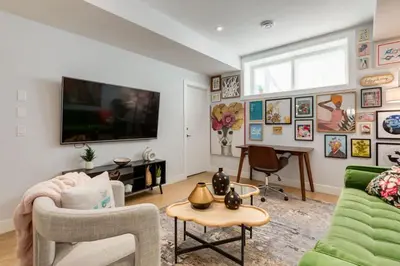a living room with a couch and a tv on the wall at Santuario Kensington - Inner City Escape in Calgary