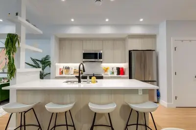 a kitchen with a white counter and stools at Santuario Kensington - Inner City Escape in Calgary