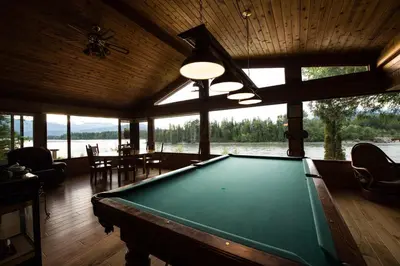 a pool table in a room with a view of the water at Skeena River House Bed & Breakfast in Terrace