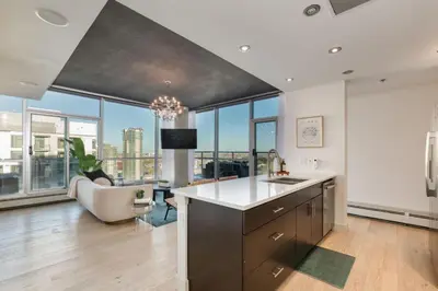a kitchen with a sink and a living room with windows at 2 Storey Penthouse Panoramic Views Parking Stampede in Calgary