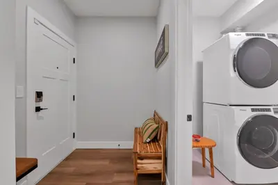a laundry room with a washing machine and a chair at Harrison Hot Springs Lakeside in Harrison Hot Springs