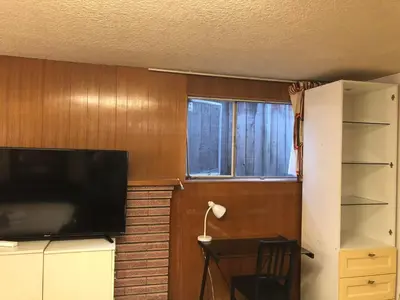 a living room with a television and a window at Comfort cottage guest home near subway station, bus and downtown in Vancouver