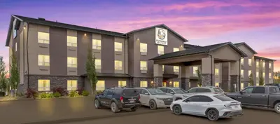 a hotel with cars parked in a parking lot at Duvernay Inn & Suites in Fox Creek