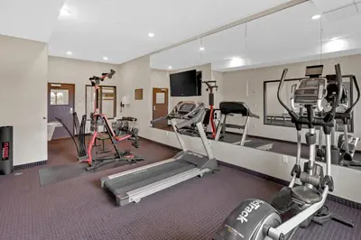 a gym with several treadmills and exercise machines at Duvernay Inn & Suites in Fox Creek