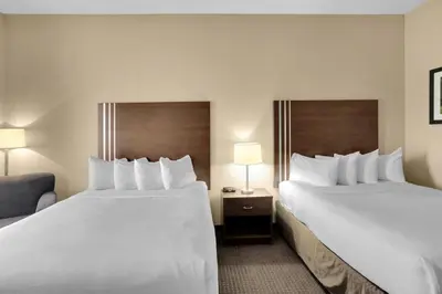 a hotel room with two beds and a chair at Duvernay Inn & Suites in Fox Creek