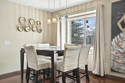 a dining room table with white chairs and a window at Calgary - By Mountains and Ski in Calgary