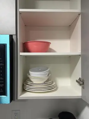 a cabinet with plates and a red bowl in it at The Nesting Cove in Airdrie