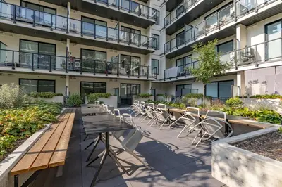 an outdoor patio with tables and chairs in front of a building at Central Kelowna TOP FLOOR rooftop patio in Kelowna