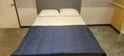 a bed with a blue blanket and two pillows at WhiteCourt in Abbotsford