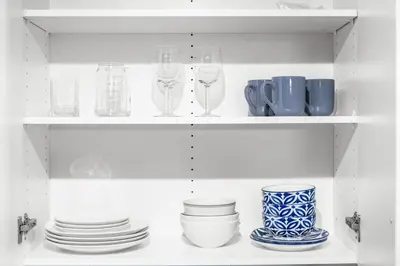 a white shelf with plates and glasses on it at Boutique-Style Studio Unit in Edmonton