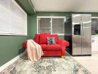 a red chair in a kitchen with a refrigerator at Bright & Spacious House Near UBC in Vancouver