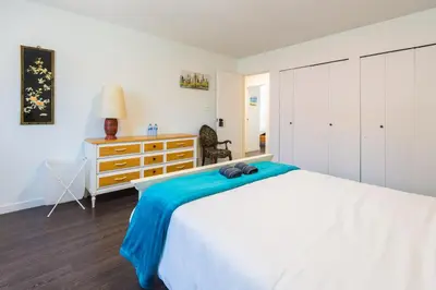 a bedroom with a white bed and a dresser at Bright & Spacious House Near UBC in Vancouver