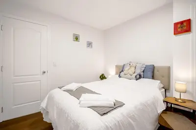 a bedroom with a white bed with towels on it at 2 Bds suite beautiful Yard near PNE in Vancouver