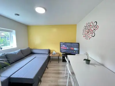 a living room with a blue couch and a tv at Top choice 2-Bed 1-Bath Garden Suite in New Westminster
