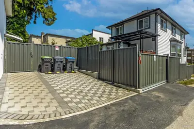 a fence with three trash cans in front of a house at Top choice 2-Bed 1-Bath Garden Suite in New Westminster