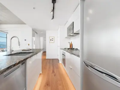 a kitchen with white appliances and a wooden floor at Modern Downtown Stay! in Vancouver