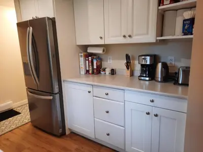 a kitchen with white cabinets and a stainless steel refrigerator at Gordon Head Bed & Breakfast 2 Bathroom 4TV 5 Beds, Private Yard, Kids Gym & Games, Breakfast, WorkStn, Laundry, Kitchen in Victoria