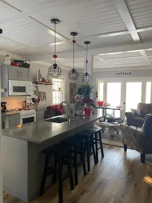 a kitchen with a large counter with stools in it at Charming Lakefront 100yr old Railway Cottage in Youbou