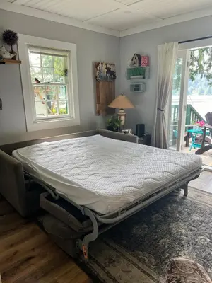a large bed in a room with a window at Charming Lakefront 100yr old Railway Cottage in Youbou