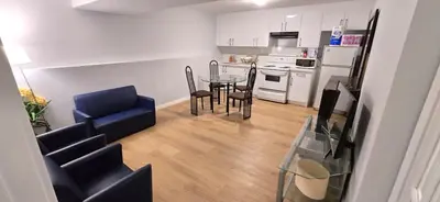 a living room with a table and chairs and a kitchen at Dream house in Edmonton