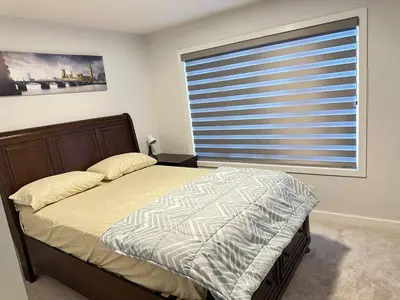 a bedroom with a bed and a large window at Relax at The Hills at Ellerslie in Edmonton