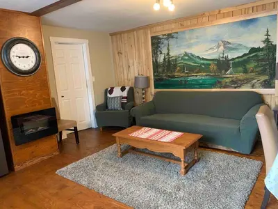 a living room with a couch and a table and a clock at Uncle Bills Cabin Entire home 6 min south of town in Golden