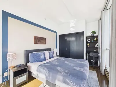a bedroom with a bed with a blue accent wall at Modern Beltline Escape Sky-High Views DT Views in Calgary