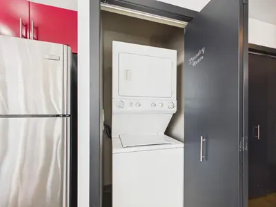 a washer and dryer in a kitchen with a refrigerator at Modern Beltline Escape Sky-High Views DT Views in Calgary