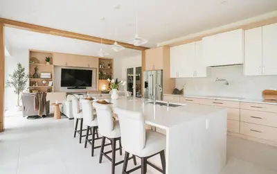 a white kitchen with a large island with white chairs at Camozzi Chalet by Revelstoke Vacations in Revelstoke