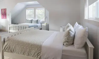 a white bedroom with a bed and a crib at Fieldstone Guesthouse in Clearwater