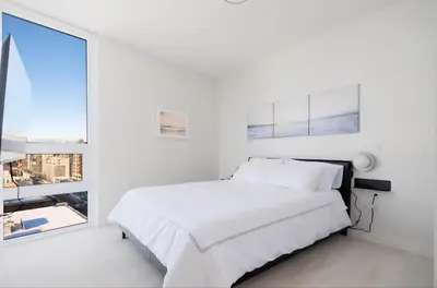 a white bedroom with a bed and a large window at Peaceful City Stay, Calm Vibes in a Cozy in Vancouver