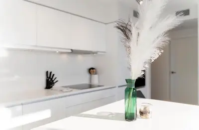 a green vase with feathers in it on a kitchen counter at Peaceful City Stay, Calm Vibes in a Cozy in Vancouver