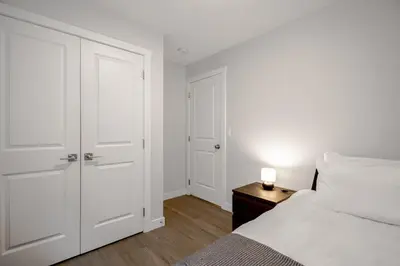 a white bedroom with a bed and a night stand with a lamp at New 2BD Suite Near Events Center in Langley