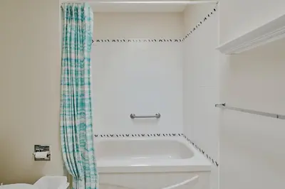 a bathroom with a tub and a shower curtain at The Coastal Garden Retreat in Delta