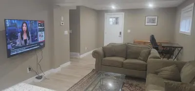 a living room with a couch and a flat screen tv at Cozy and Affordable Apartment - Guesthouse South West Airdrie in Airdrie