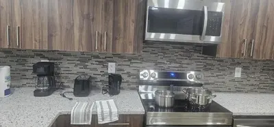 a kitchen with a stove and a microwave at Cozy and Affordable Apartment - Guesthouse South West Airdrie in Airdrie
